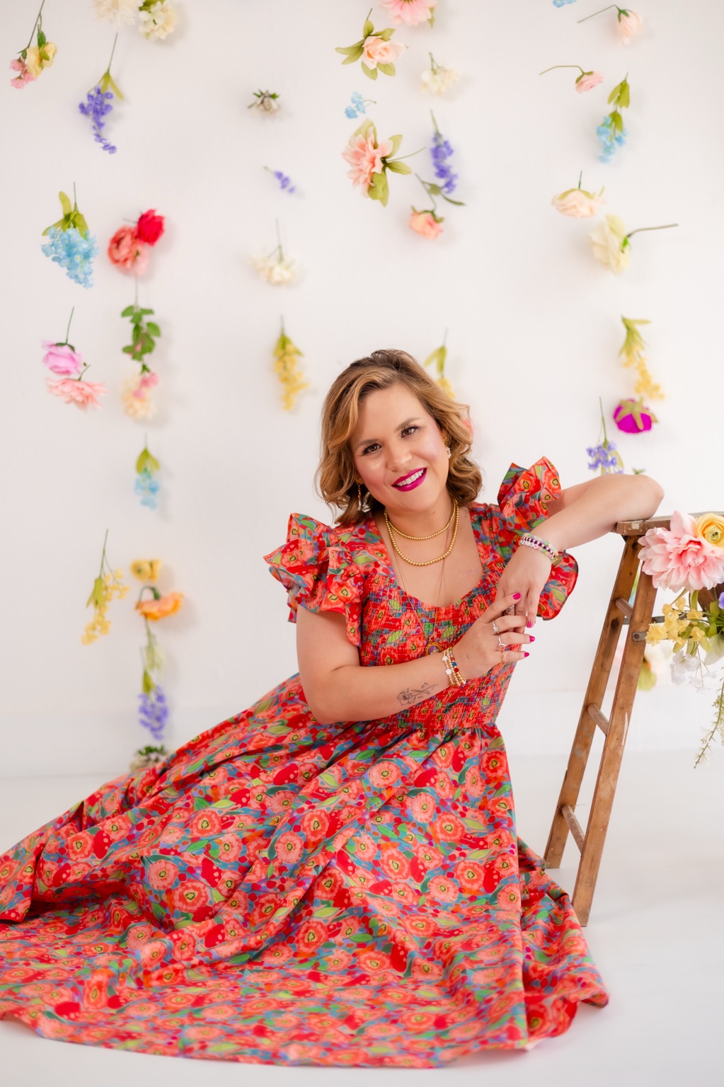 Remy Uhler, therapist and founder of The Processing Hour Therapy Co., seated beside a floral display.